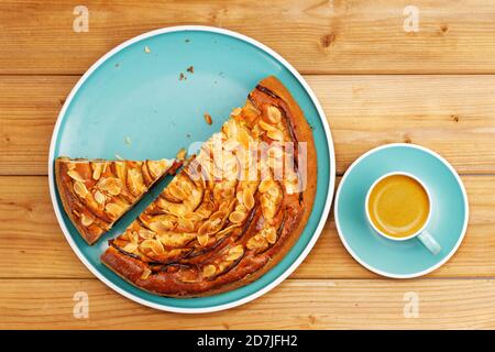 Hausgemachter Kuchen mit Äpfeln und Pflaumen mit Mandelblüten und Tasse Kaffee Espresso auf Holztisch. Draufsicht. Stockfoto