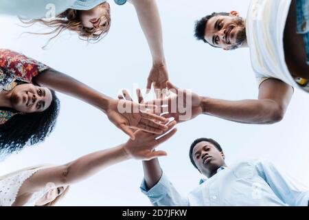 Low-Angle-Ansicht von Freunden bringen ihre Hände zusammen in Zeigen der Einheit vor dem Spiel Stockfoto
