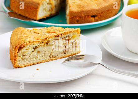 Closeup Stück Apfelkuchen mit Mandelblüten auf weißem Holztisch. Geringer Fokus. Stockfoto