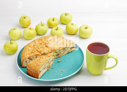 Hausgemachtes Gebäck. Apfelkuchen mit Mandelblüten und einer Tasse Tee auf einem weißen Holztisch. Stockfoto