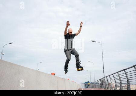 Junger Mann mit Inline-Skates springen auf Brücke gegen Himmel Stockfoto