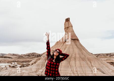 Spanien, Navarra, Portrait der weiblichen Touristen stehend mit erhobenen Armen vor Sandsteinfelsen in Bardenas Reales Stockfoto