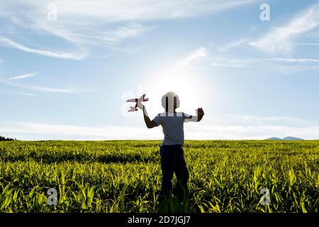 Silhouette des Jungen spielt mit Flugzeug Spielzeug gegen klaren Himmel Stockfoto