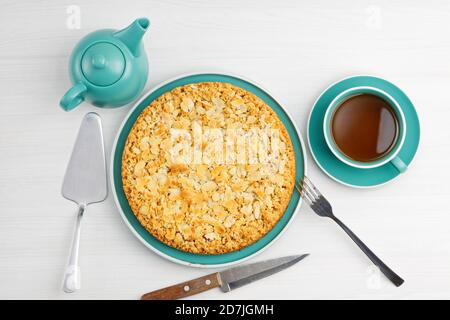 Apfelkuchen mit Mandelblüten und einer Tasse Tee auf einem weißen Holztisch. Draufsicht. Stockfoto