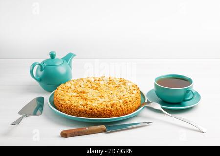 Apfelkuchen mit Mandelblüten und einer Tasse Tee auf einem weißen Holztisch. Copyspace. Stockfoto