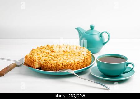 Apfelkuchen mit Mandelblüten und einer Tasse Tee auf einem weißen Holztisch. Copyspace. Stockfoto