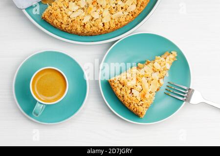 Apfelkuchen mit Mandelblüten und Tasse Kaffee Espresso auf weißem Holztisch. Draufsicht. Stockfoto