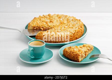 Apfelkuchen mit Mandelblüten und Tasse Kaffee Espresso auf weißem Holztisch. Stockfoto