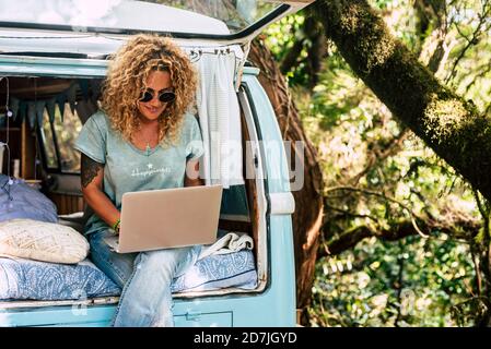 Frau trägt Sonnenbrille mit Laptop, während sie auf dem Bett sitzt Vintage-Wohnmotorhaus Stockfoto