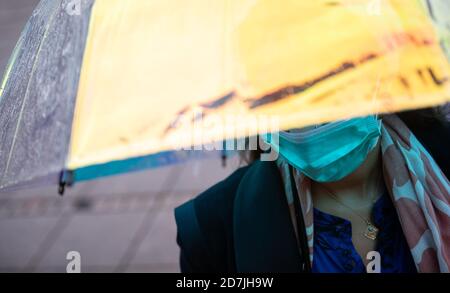 Stuttgart, Deutschland. Oktober 2020. Eine Frau steht in der Innenstadt mit einem reflektierenden Regenschirm. Quelle: Sebastian Gollnow/dpa/Alamy Live News Stockfoto