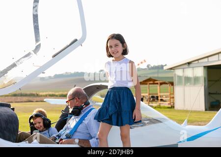 Schwester steht neben Großvater und Bruder sitzen im Flugzeug Stockfoto