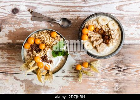 Zwei Schalen Haferbrei mit Hafer, Leinsamen, Winterkirschen und Bananen Stockfoto