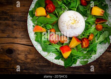 Teller mit frischem vegetarischen Salat mit Tomaten, Basilikum, Rucola, Nektarinen, Zitronenmelisse und Burrata-Käse Stockfoto