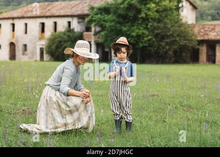Mutter und Sohn sammeln Blumen, während sie in Meadowe stehen Stockfoto