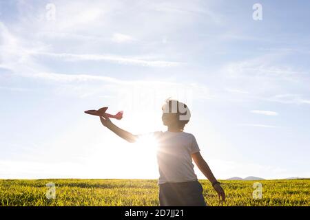 Junge spielt mit Flugzeug Spielzeug, während sie gegen klar stehen Himmel Stockfoto