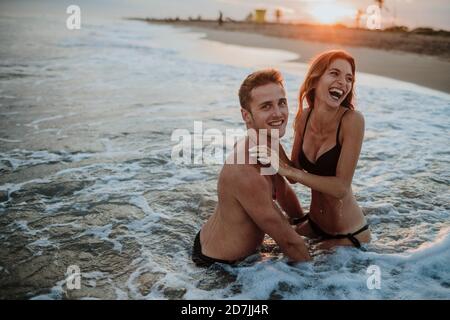 Glückliches Paar, das am Strand im Wasser genießt Stockfoto