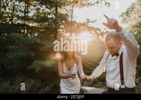 Pärchen genießen beim Tanzen im Wald während des Sonnenuntergangs Stockfoto