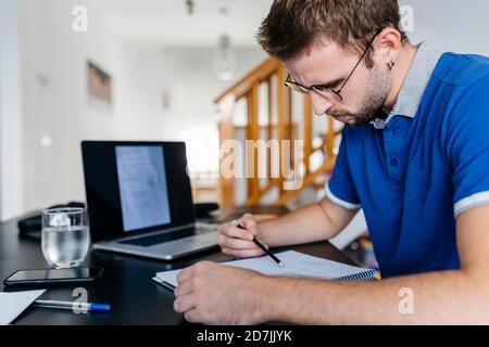 Engagierter junger männlicher Universitätsstudent, der zu Hause Mathematik macht Stockfoto