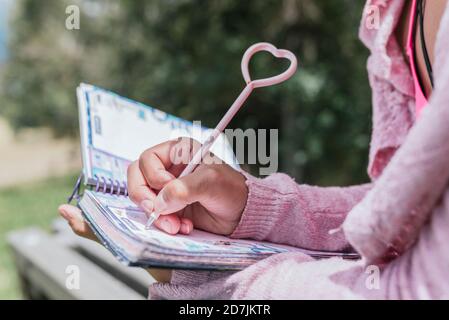 Nahaufnahme einer jungen Frau, die im Park Tagebuch schreibt Stockfoto