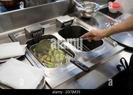 Männlicher Koch kocht Jalapeno Paprika in Fritteuse im Handel Küche Stockfoto