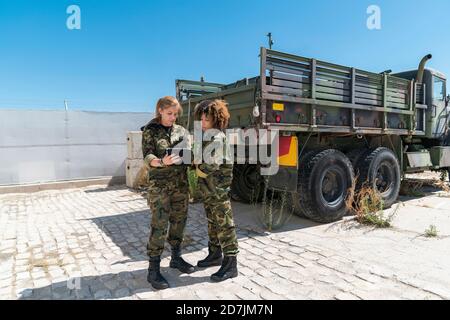 Weibliche Soldaten Armee diskutieren über digitale Tablette auf Militärbasis An sonnigen Tag Stockfoto