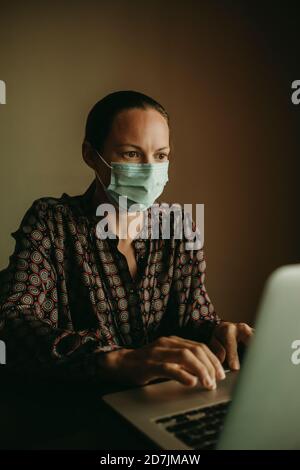 Konzentriert weibliche Unternehmer tragen Schutzmaske auf Laptop arbeiten Im Büro Stockfoto