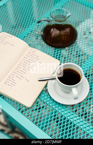 Man konnte das Buch, die Kaffeetasse und die Kanne auf dem Tisch sehen Stockfoto