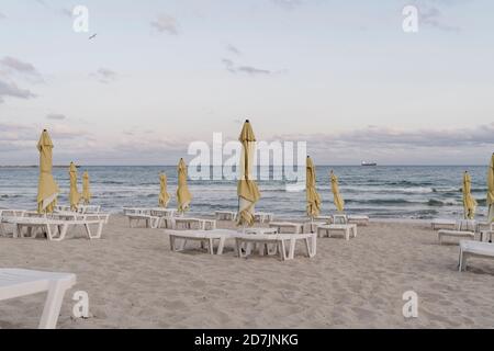 Sonnenschirme und Liegestühle am leeren Strand in der Abenddämmerung Stockfoto