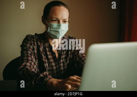 Weibliche Unternehmer tragen schützende Gesichtsmaske arbeiten auf Laptop in Büro während des Covid-19 Stockfoto