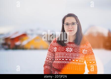 Lächelnde junge Frau, die auf schneebedecktem Land gegen den Himmel steht Stockfoto