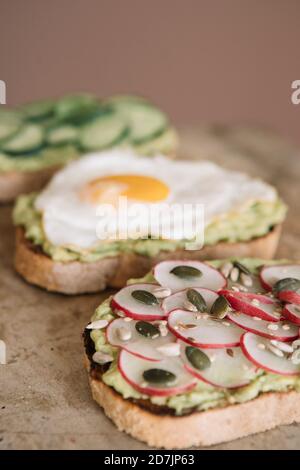 Braunes Brot garniert mit Guacamole und Gemüse auf Servierplatte In der Küche Stockfoto