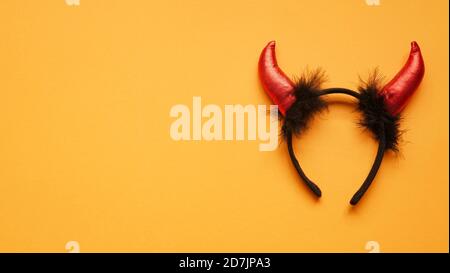 Red Devil Hörner Kopf Reifen auf Orang Hintergrund. Zubehör für Halloween-Feier, Draufsicht, flache Lay, Kopierraum. Stockfoto