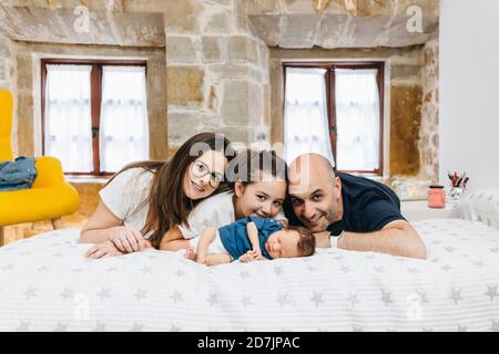 Lächelnde Familie, die zu Hause im Schlafzimmer auf dem Bett liegt Stockfoto
