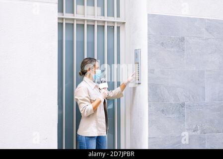 Journalistin trägt Maske mit Mikrofon am Eingang des Gebäude Stockfoto