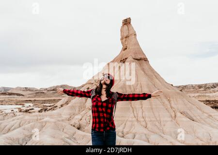 Spanien, Navarra, Portrait der weiblichen Touristen stehend mit erhobenen Armen vor Sandsteinfelsen in Bardenas Reales Stockfoto