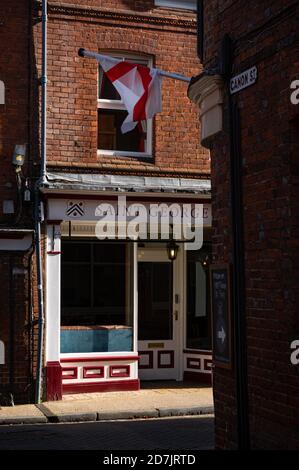 Eine Flagge von St. George (die englische Nationalflagge) ist gegenüber den St. George Tea Rooms am Ende der Canon Street in Winchester, Hampshire, England zu sehen Stockfoto