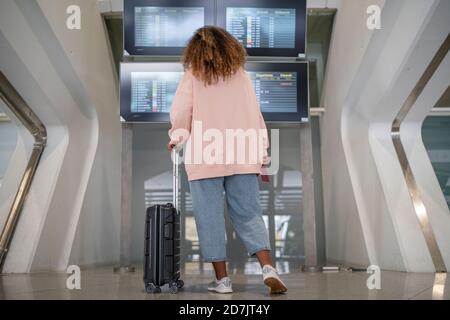 Junge Frau, die an Bord nach dem Flugplan checkt flughafen Stockfoto