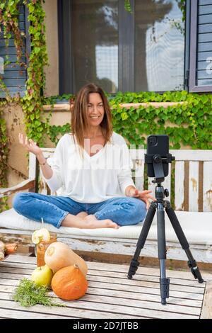 Lächelnde Ernährungsberaterin vlogging durch Smartphone im Hinterhof Stockfoto