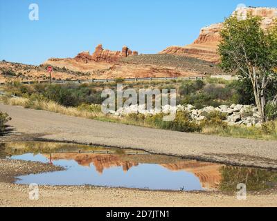 Ein Regenbecken aus dem Regen der Vornacht, das die Sandstein-Felsformationen im Castle Valley in Utah, USA, widerspiegelt Stockfoto