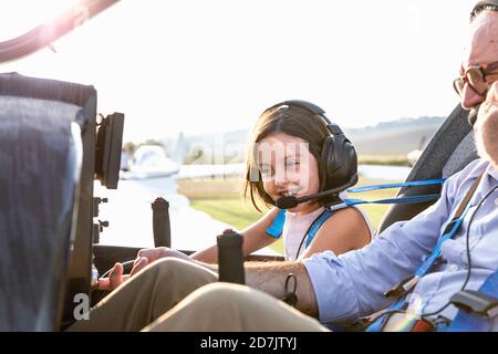 Junges kleines Mädchen im Flugzeug-Cockpit mit Großvater auf dem Flugplatz An sonnigen Tag Stockfoto