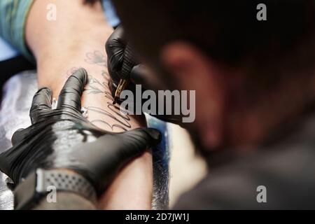 Nahaufnahme der Tätowierung eines männlichen Künstlers an der Hand des Kunden im Studio Stockfoto