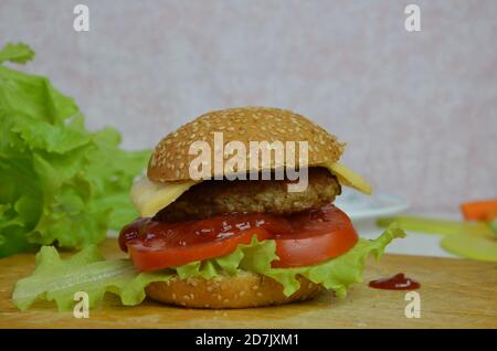 Hausgemachter Hamburger mit Rindfleisch, Zwiebeln, Tomaten, Salat und Käse. Frischer Burger aus der Nähe auf rustikalem Holztisch Stockfoto