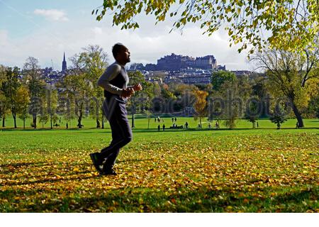 Edinburgh, Schottland, Großbritannien. Oktober 2020. Nach einem regnerischen und bewölkten Morgen wird das Wetter klar und die Menschen tauchen auf, um die Natur und Herbstfarben im Inverleith Park zu genießen. Joggen im Park mit Blick auf das Edinburgh Castle. Kredit: Craig Brown/Alamy Live Nachrichten Stockfoto