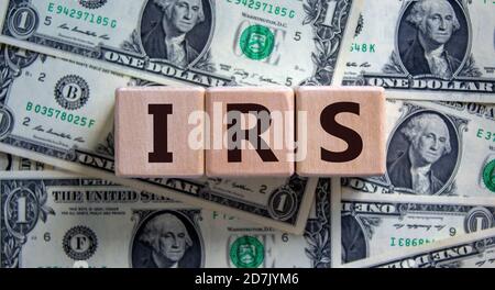 Konzeptwort 'IRS - Internal Revenue Service' auf Holzblöcken auf einem schönen Hintergrund von Dollarscheinen. Geschäftskonzept. Stockfoto