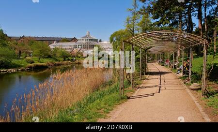 Kopenhagen, Dänemark - 04/29/2019: Menschen sitzen auf Bänken genießen die Frühlingssonne im botanischen Garten (Botanisk haben) in Kopenhagen Zentrum. Stockfoto