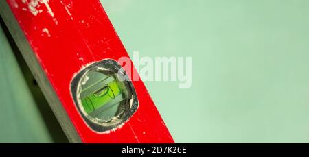 Werkzeugebene wird gebaut. Rotes Wasserstufe-Werkzeug auf grünem Hintergrund isoliert. Konzept. Speicherplatz kopieren. Stockfoto