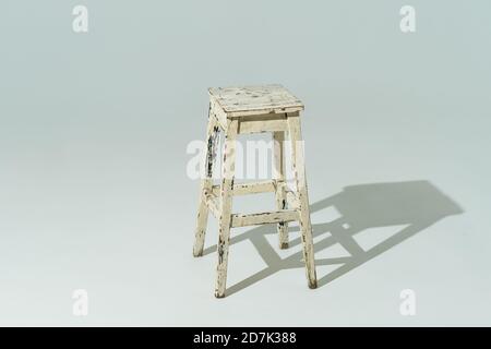 Hoher Retro-Hocker oder Tabouret mit abblätternder weißer Farbe auf weißem Hintergrund. Leerer Ort Stockfoto