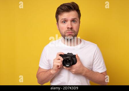 Studio-Porträt von schönen jungen Mann hält Fotokamera in Einstellungen verwirrt. Stockfoto