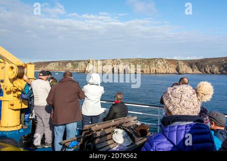 Passagiere auf dem Scillonian, der Fähre, die von Penzance zu den Scilly Isles fährt, vorbei an Meeresklippen in der Nähe von Porthcurno. Stockfoto