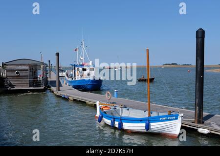 Wells Harbour Norfolk UK zeigt 2 festgeklammerte Boote, eines davon ist ein traditionelles Holz mit offenem Klinker gebaut Handwerk, mit klarem blauen Himmel. Stockfoto